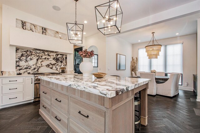 557 Greenwood Ave SE, East Grand Rapids, MI 49506 - kitchen featuring a notable chandelier, tasteful backsplash, a breakfast bar, a center island, and stainless steel stove