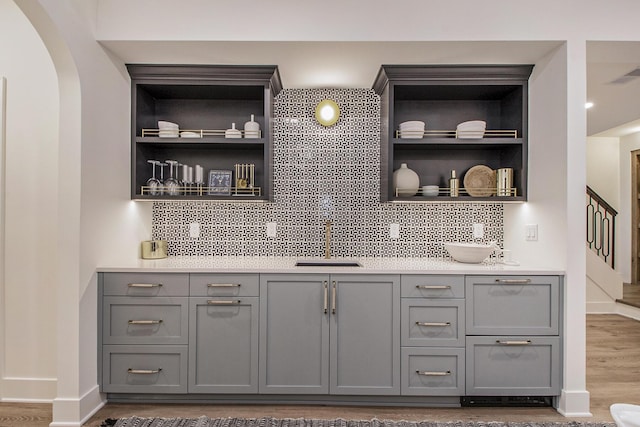 557 Greenwood Ave SE, East Grand Rapids, MI 49506 - bar featuring a sink, tasteful backsplash, wood finished floors, visible vents, and arched walkways