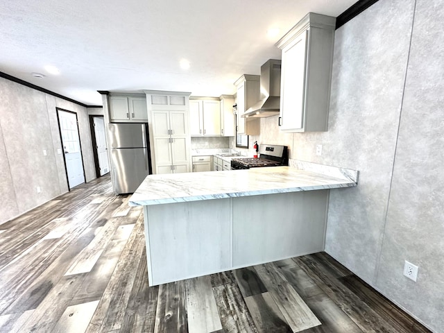 3502 Beech Ln, Twin Lake, MI 49457 - kitchen with wall chimney range hood, appliances with stainless steel finishes, dark wood finished floors, light stone countertops, and a peninsula