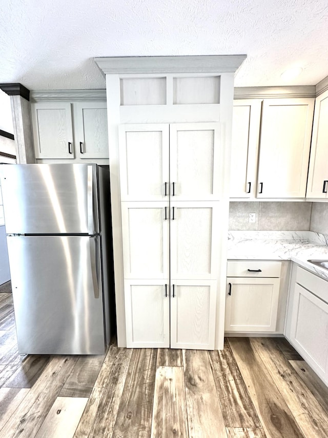 3502 Beech Ln, Twin Lake, MI 49457 - kitchen with freestanding refrigerator, light wood-style floors, a textured ceiling, and light stone countertops