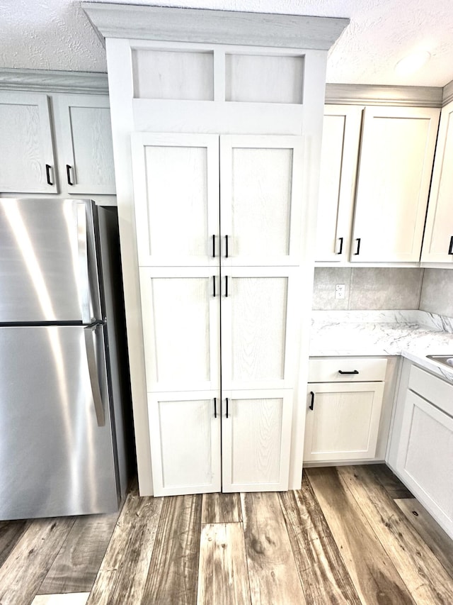 3502 Beech Ln, Twin Lake, MI 49457 - kitchen featuring freestanding refrigerator, a textured ceiling, light wood finished floors, and light stone countertops