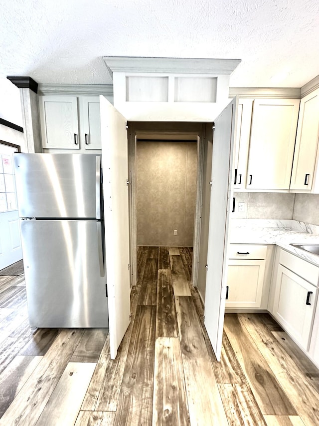 3502 Beech Ln, Twin Lake, MI 49457 - kitchen with freestanding refrigerator, light wood-style flooring, a textured ceiling, and light stone counters