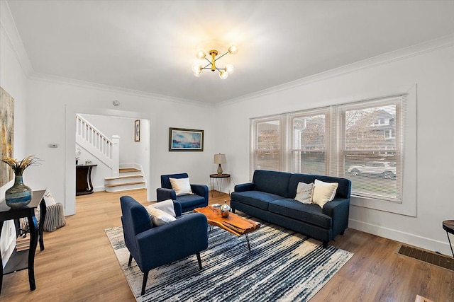 living area featuring light wood finished floors, crown molding, an inviting chandelier, and stairway