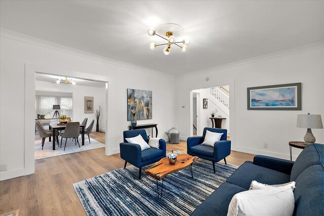 living room with a chandelier, crown molding, light wood-style floors, and stairway