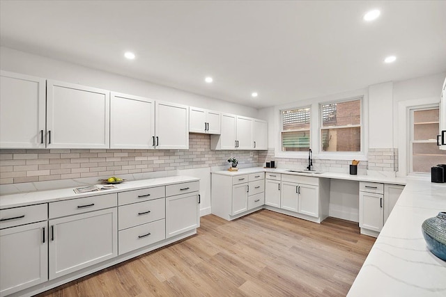 kitchen featuring light stone counters, recessed lighting, light wood-style flooring, decorative backsplash, and a sink