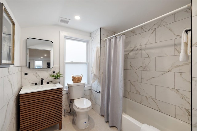 bathroom with vanity, visible vents, toilet, tile walls, and shower / bath combo with shower curtain