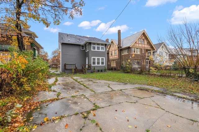 rear view of house featuring fence and a lawn