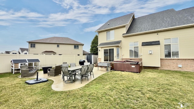 rear view of property featuring a hot tub, fence, a lawn, and a patio area