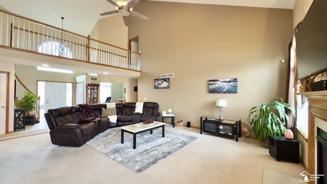 carpeted living area featuring a towering ceiling, visible vents, ceiling fan, and a fireplace