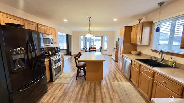 kitchen with light countertops, a sink, a breakfast bar area, appliances with stainless steel finishes, and light wood-type flooring