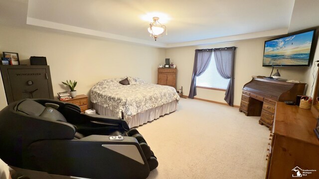 bedroom featuring a tray ceiling, baseboards, and light carpet