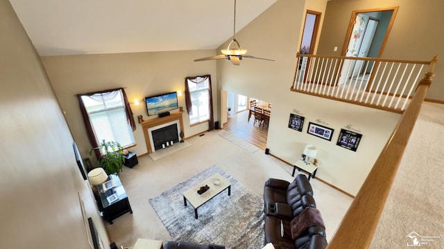 carpeted living room with a fireplace, high vaulted ceiling, baseboards, and a ceiling fan