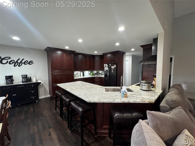 56098 Walker Ct, Macomb, MI 48042 - kitchen featuring black fridge, a sink, a peninsula, wall chimney exhaust hood, and recessed lighting