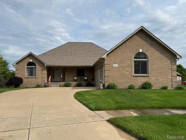 56098 Walker Ct, Macomb, MI 48042 - ranch-style home featuring brick siding, a garage, covered porch, a front lawn, and driveway