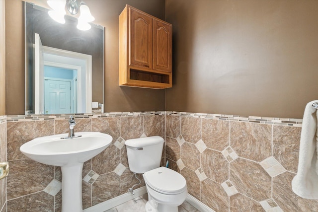 half bathroom with toilet, tile walls, and a chandelier
