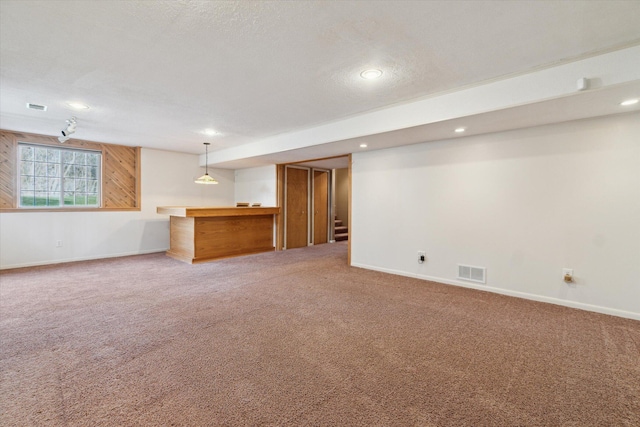 below grade area featuring baseboards, visible vents, bar, and light colored carpet
