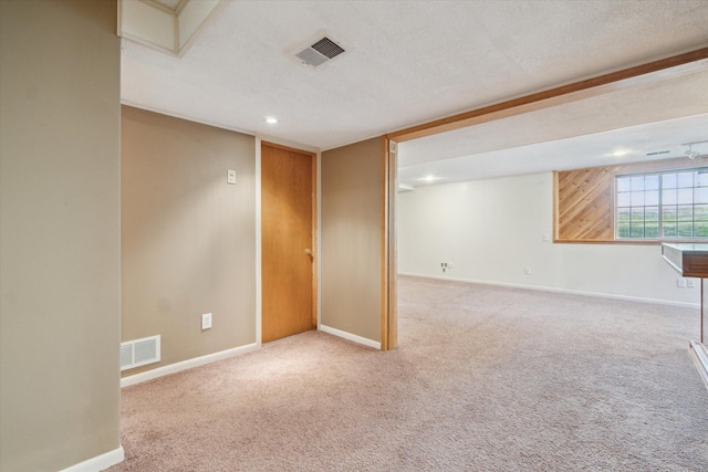 below grade area with carpet flooring, a textured ceiling, baseboards, and visible vents