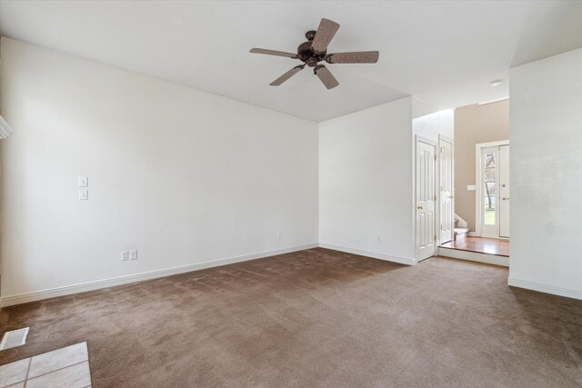 unfurnished living room with carpet floors, baseboards, visible vents, and ceiling fan