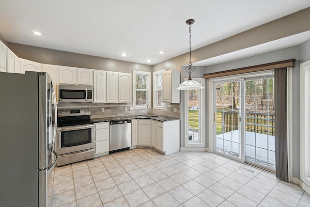 kitchen featuring tasteful backsplash, plenty of natural light, pendant lighting, white cabinets, and appliances with stainless steel finishes