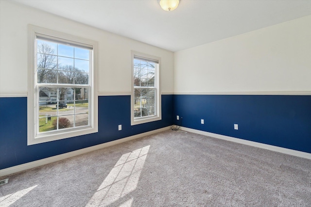 carpeted spare room with baseboards and visible vents