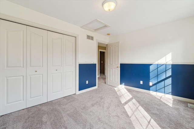 unfurnished bedroom featuring attic access, visible vents, a closet, and carpet floors
