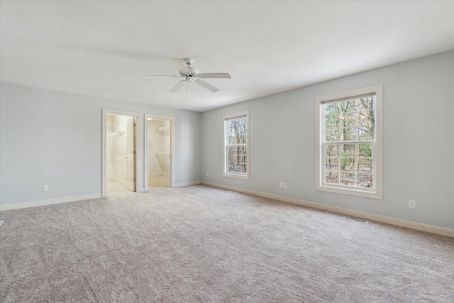 carpeted spare room featuring baseboards, visible vents, and a ceiling fan