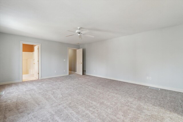 carpeted spare room featuring baseboards and a ceiling fan