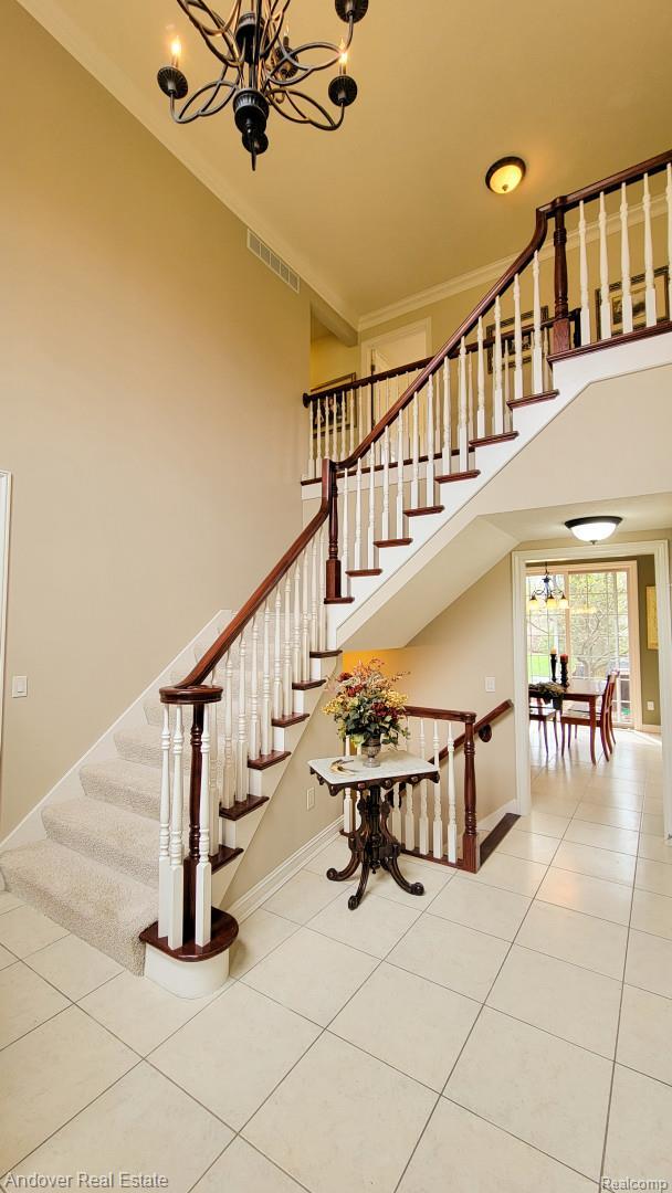 2004 Timberview Dr, Okemos, MI 48864 - staircase featuring a chandelier, tile patterned flooring, a towering ceiling, and baseboards