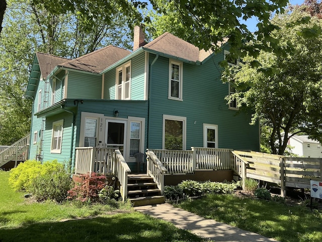 121 W State St, Reading, MI 49274 - rear view of house featuring a chimney, a deck, a lawn, and roof with shingles