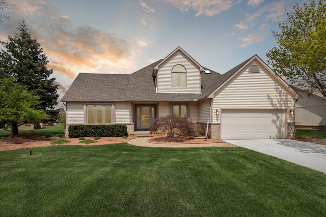 traditional-style house featuring a shingled roof, an attached garage, brick siding, a lawn, and driveway
