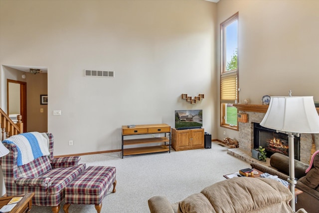 living room featuring carpet floors, a warm lit fireplace, and a healthy amount of sunlight