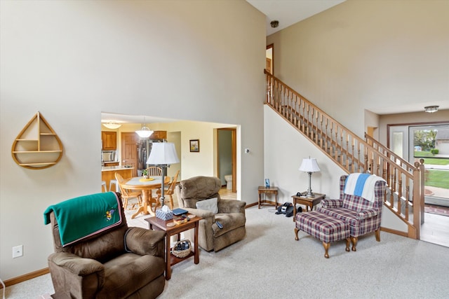 living area with carpet floors, baseboards, a high ceiling, and stairway