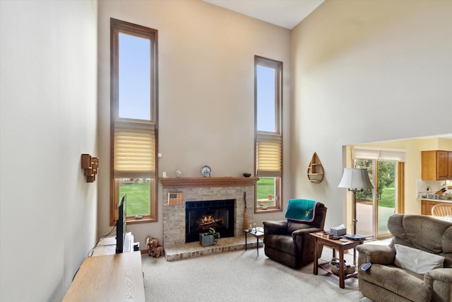living area featuring a high ceiling, a brick fireplace, and carpet flooring