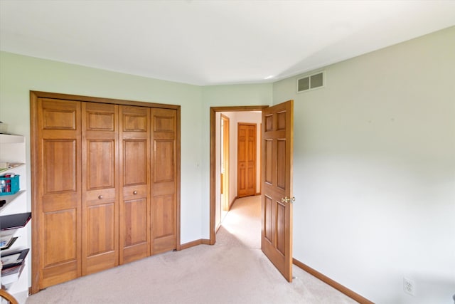 unfurnished bedroom featuring visible vents, baseboards, a closet, and light colored carpet