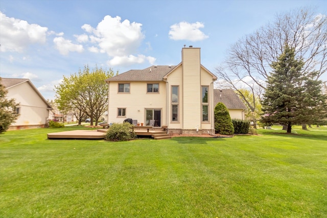 back of property with a yard, a wooden deck, and a chimney