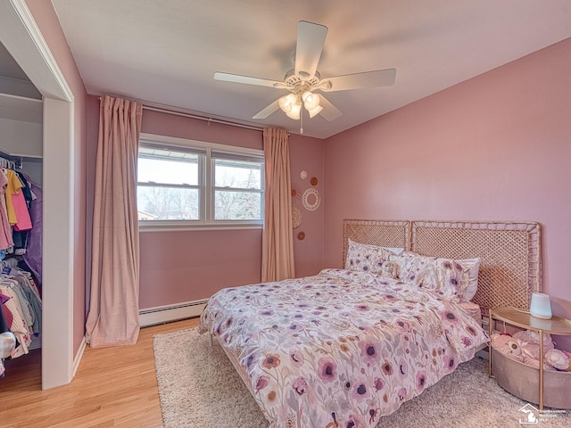 bedroom featuring a closet, ceiling fan, light wood-type flooring, and a baseboard radiator