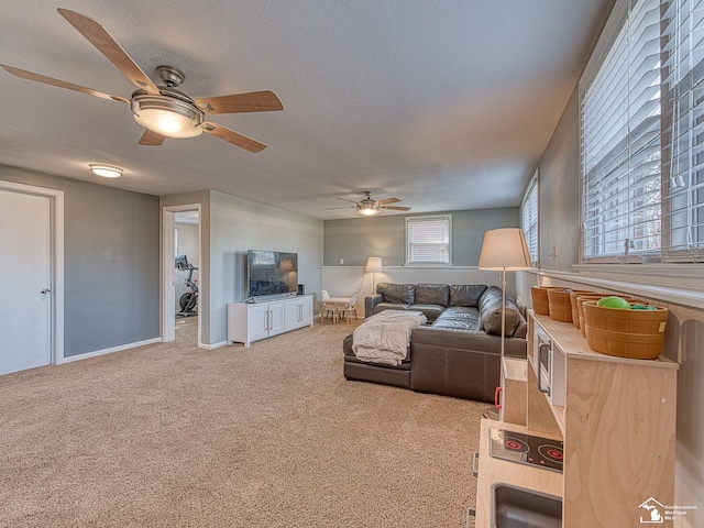 living room with carpet, baseboards, a textured ceiling, and ceiling fan