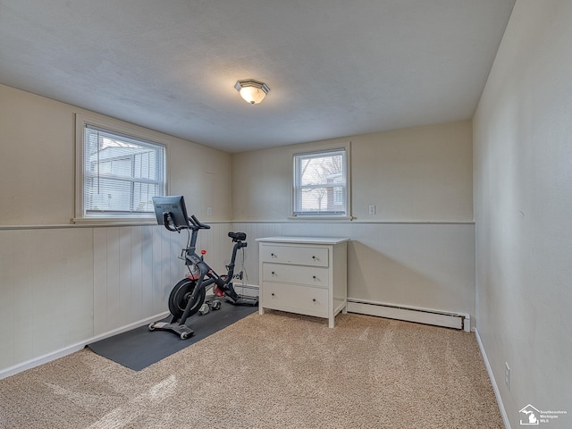 workout room featuring a wainscoted wall, a baseboard heating unit, and carpet
