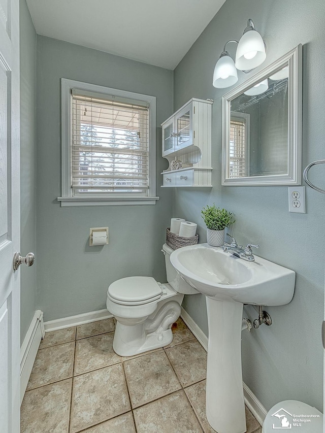 half bathroom featuring baseboards, toilet, a baseboard heating unit, and tile patterned flooring