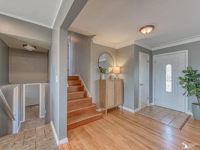 entryway with baseboards, stairs, ornamental molding, and wood finished floors