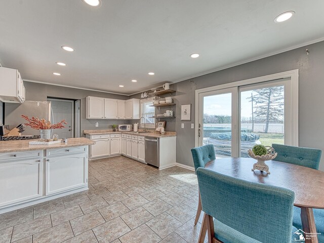 kitchen featuring light countertops, white cabinets, crown molding, stainless steel appliances, and a sink