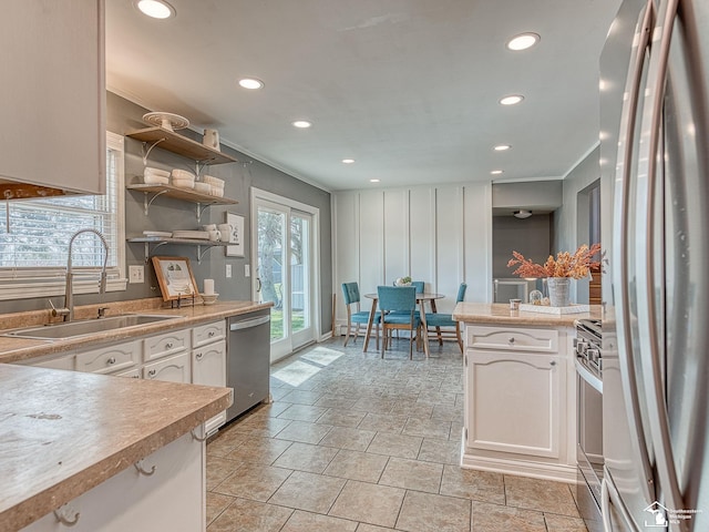 kitchen with light countertops, a sink, stainless steel appliances, and open shelves
