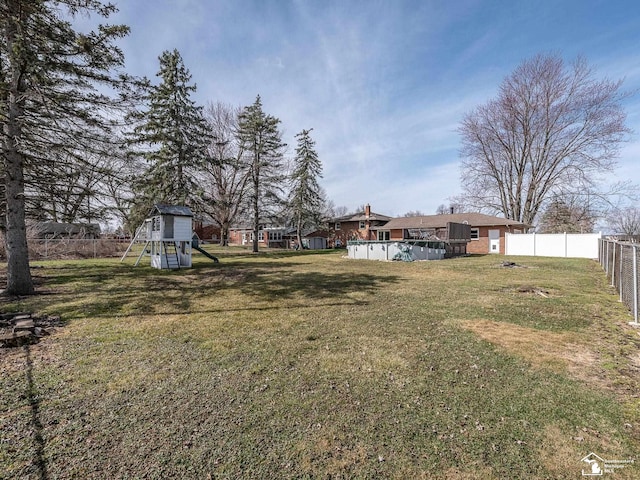 view of yard with a fenced backyard, a playground, and an outdoor pool