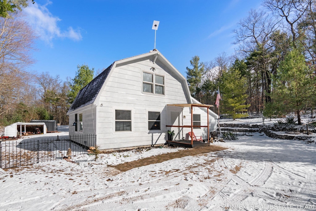 snow covered house with a gambrel roof and a shingled roof