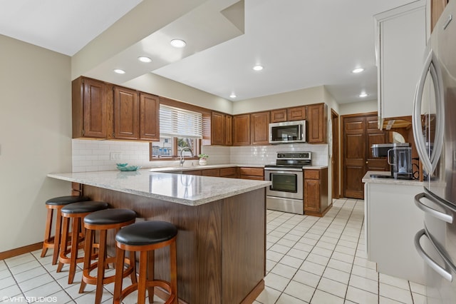 4129 Hailey Dr, Saint Joseph, MI 49085 - kitchen featuring light tile patterned floors, a peninsula, appliances with stainless steel finishes, and decorative backsplash