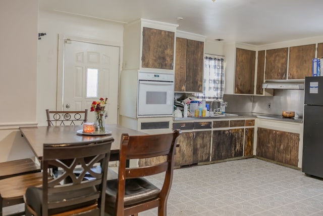 12600 Hayes St, Detroit, MI 48205 - kitchen featuring black appliances, dark brown cabinets, under cabinet range hood, a sink, and light countertops