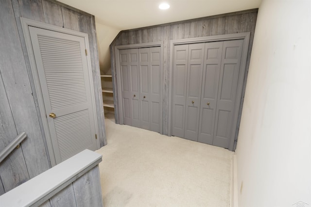 hall with carpet floors and vaulted ceiling