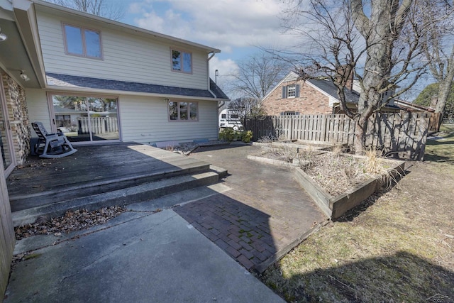 rear view of house with a patio area, a deck, fence, and a garden