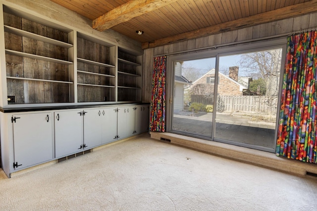 empty room with visible vents, beamed ceiling, light carpet, built in features, and wood ceiling