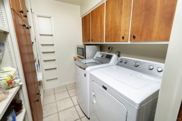laundry room featuring light tile patterned flooring, washing machine and dryer, and cabinet space